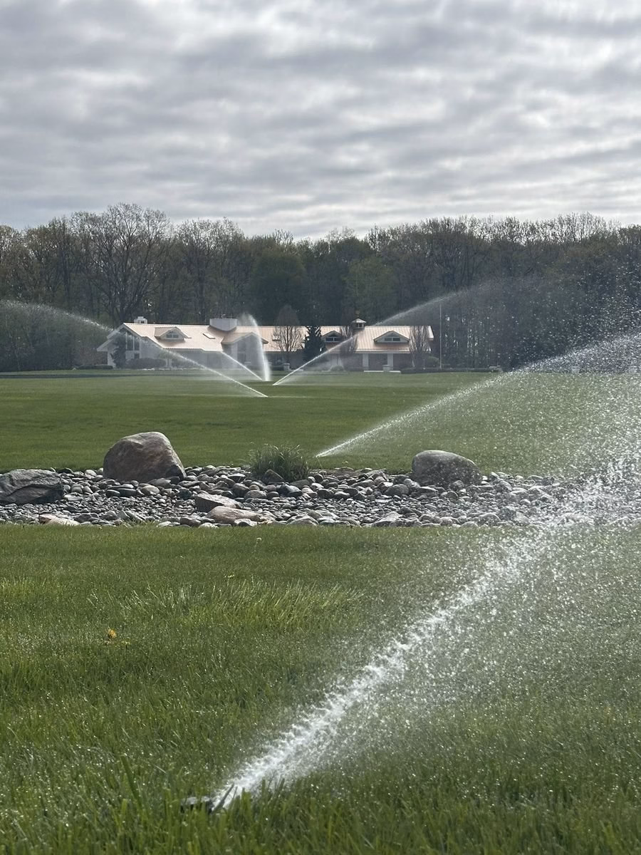 Landscaped lawn with a rock border and sprinklers running